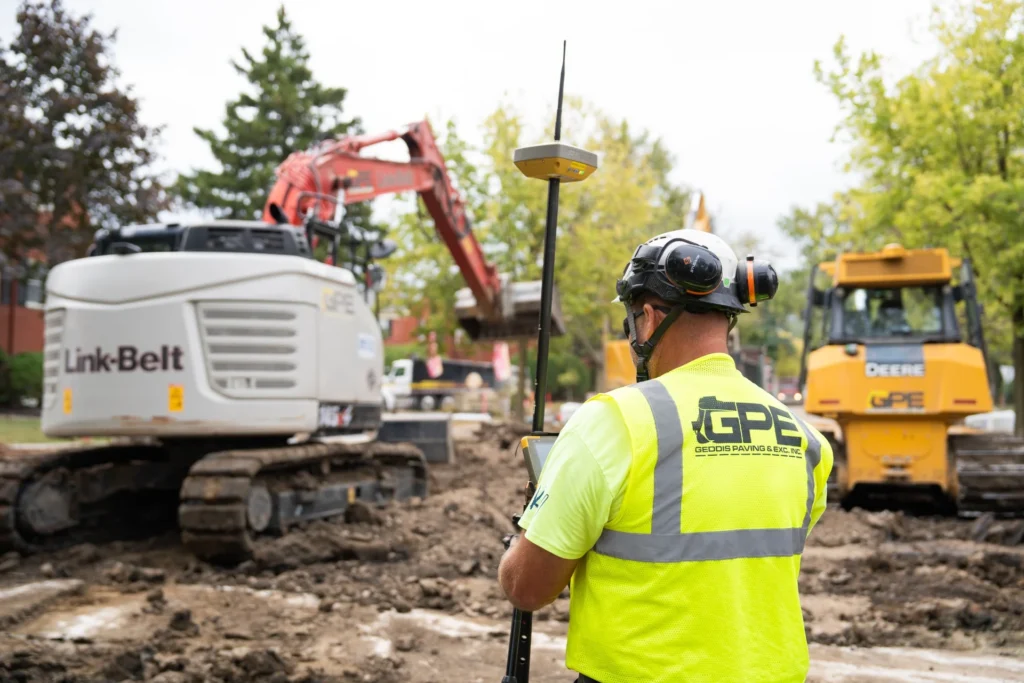 Team member of NW Ohio excavation company Geddis Paving & Excavating using advanced equipment on a construction site, highlighting the company’s evolution from a single backhoe to a full-service contractor.